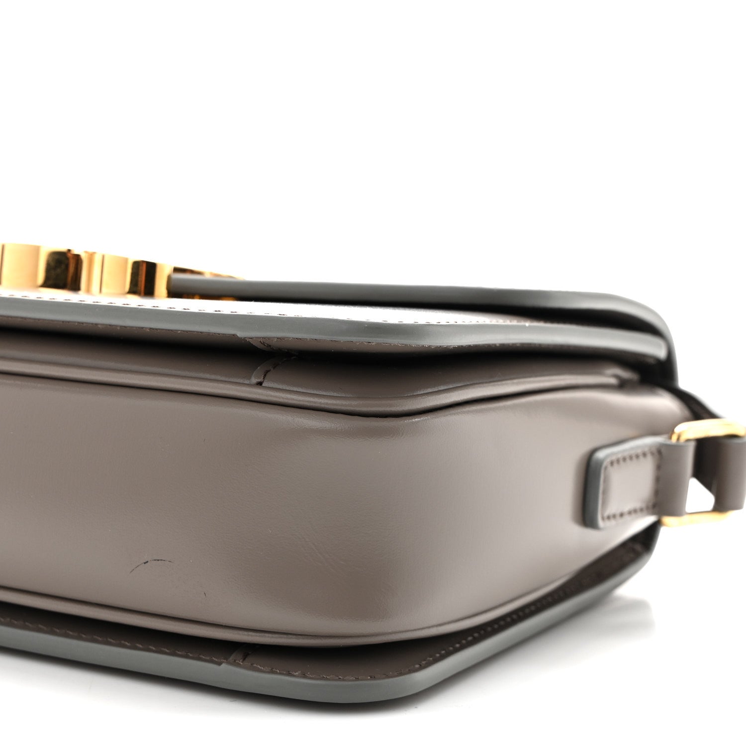 Celine shiny calfskin bag corner detail with gold-tone bar and strap hardware, light gray