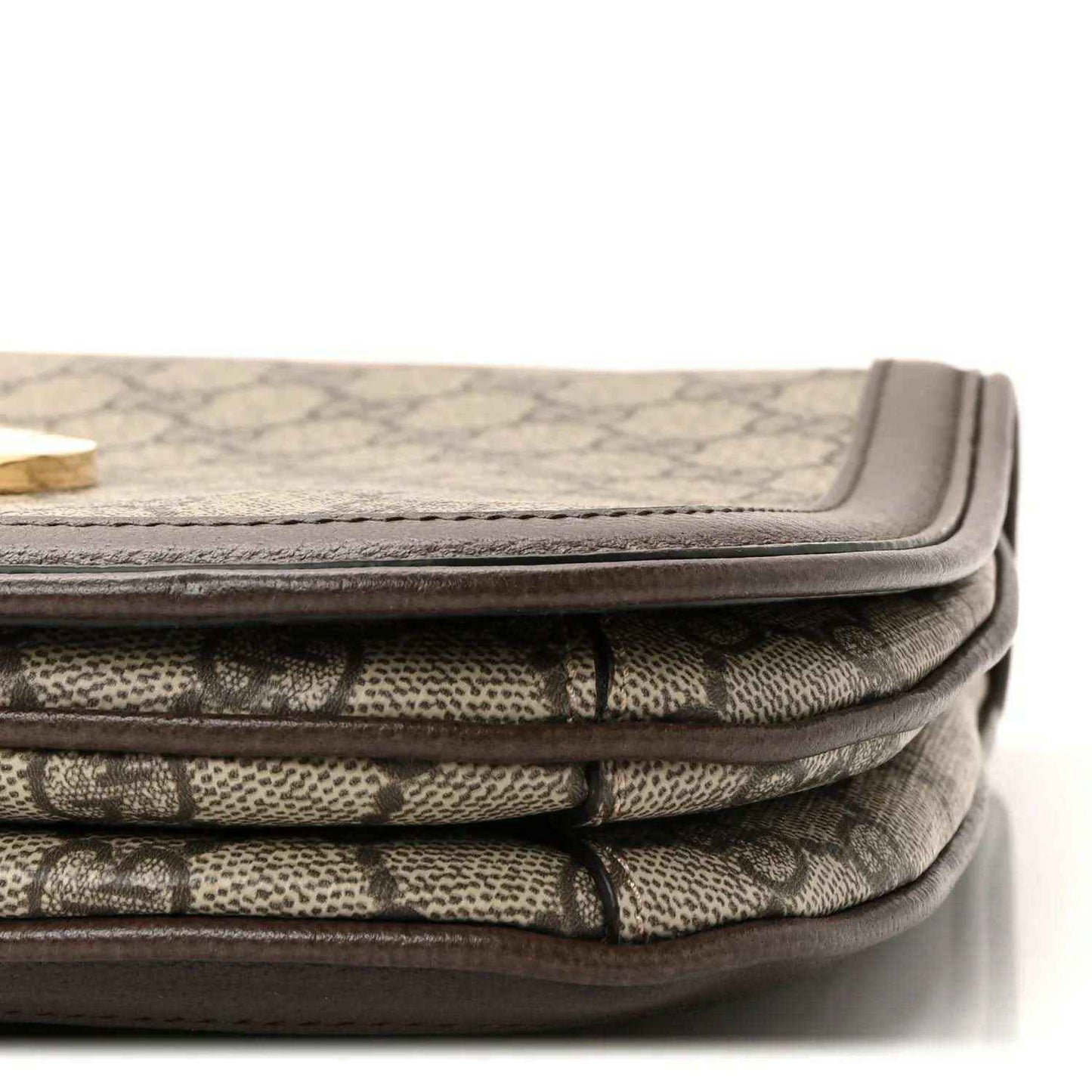 Bag corner showing beige GG monogram canvas folds with brown leather binding