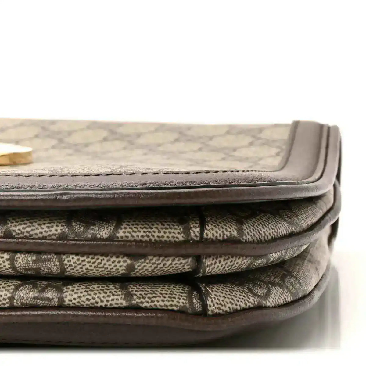 Bag corner showing beige GG monogram canvas folds with brown leather binding