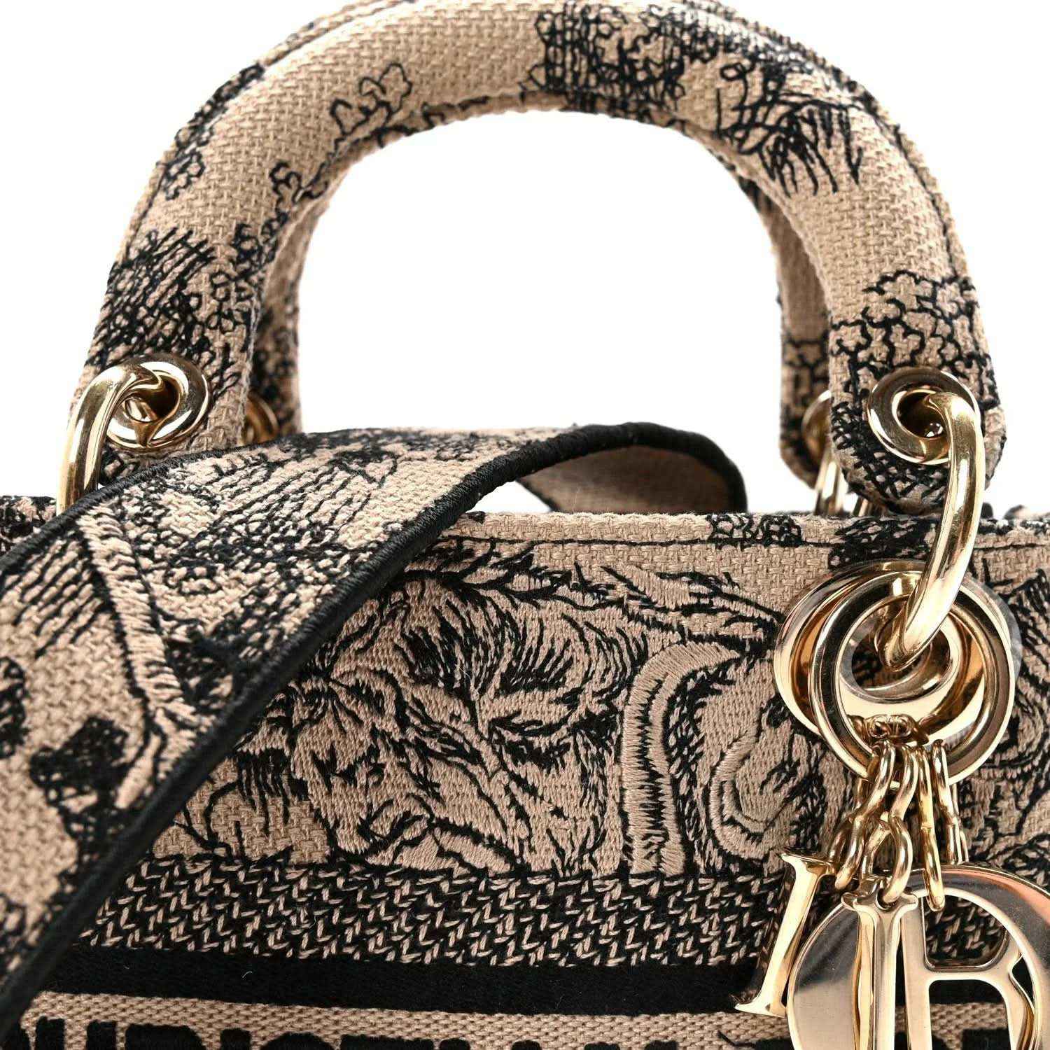 Top handles and gold chain charm on a black-and-cream embroidered mini handbag