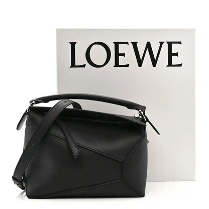 Small black calfskin shoulder bag with top handle, shoulder strap, and front flap