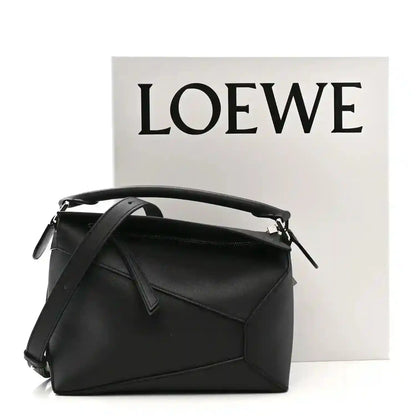 Small black calfskin shoulder bag with top handle, shoulder strap, and front flap