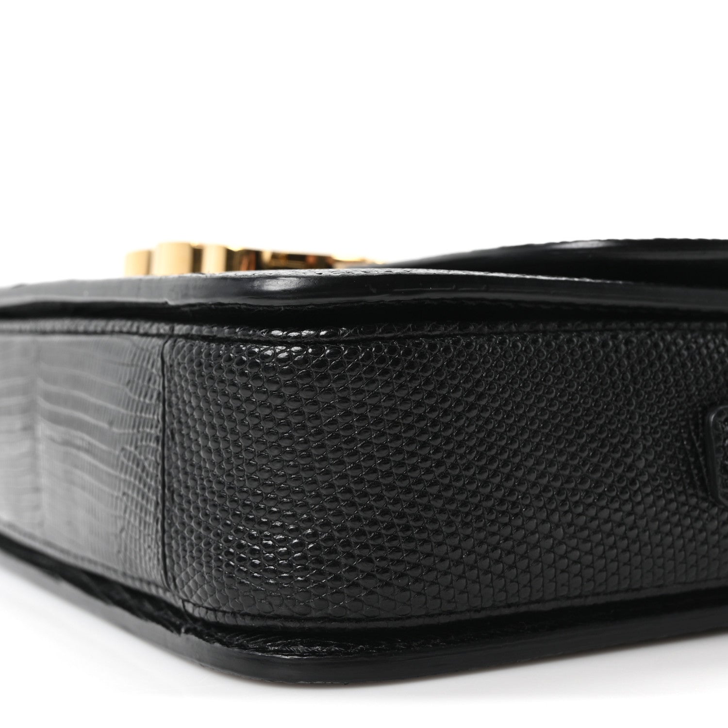 Black lizard-embossed flap bag side with gold hardware peeking