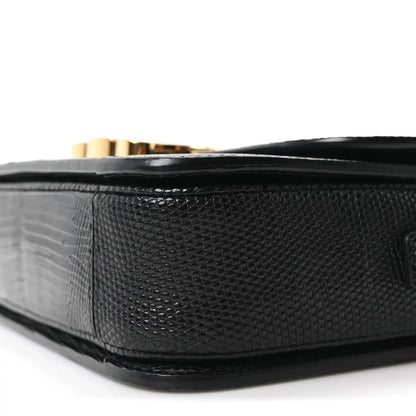 Black lizard-embossed flap bag side with gold hardware peeking