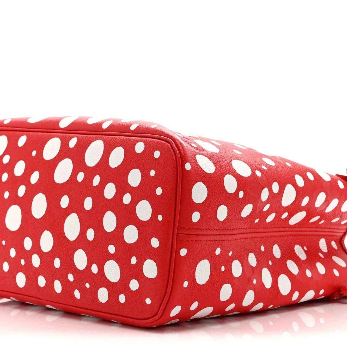 Red polka-dot tote bag close-up showing side seam and smooth leather panel