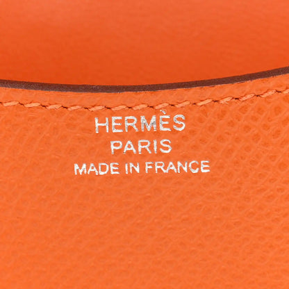 Hermes Paris Made in France stamp on orange leather slim wallet.