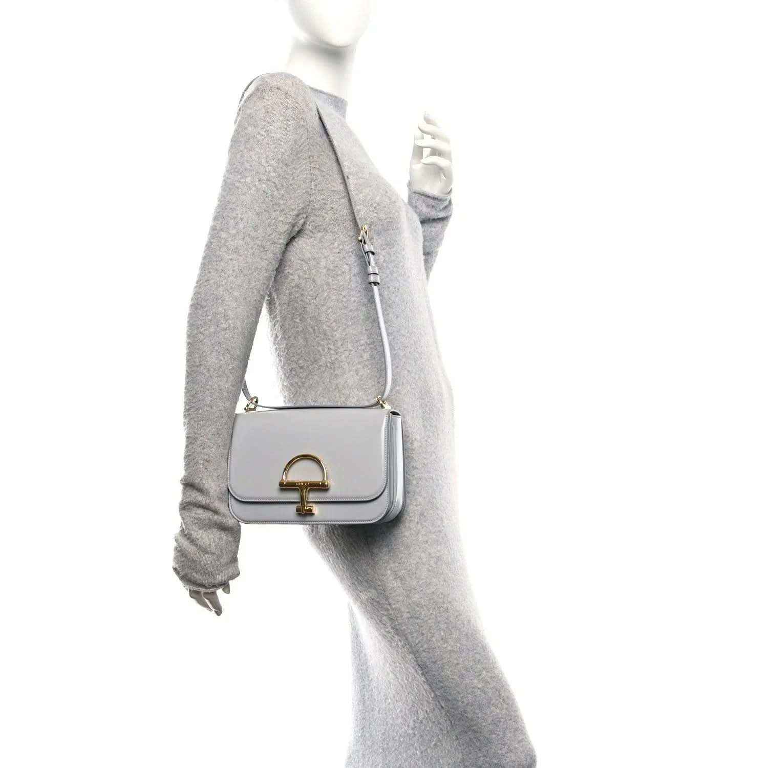 Light grey small shoulder bag on model with gold-tone clasp and adjustable strap
