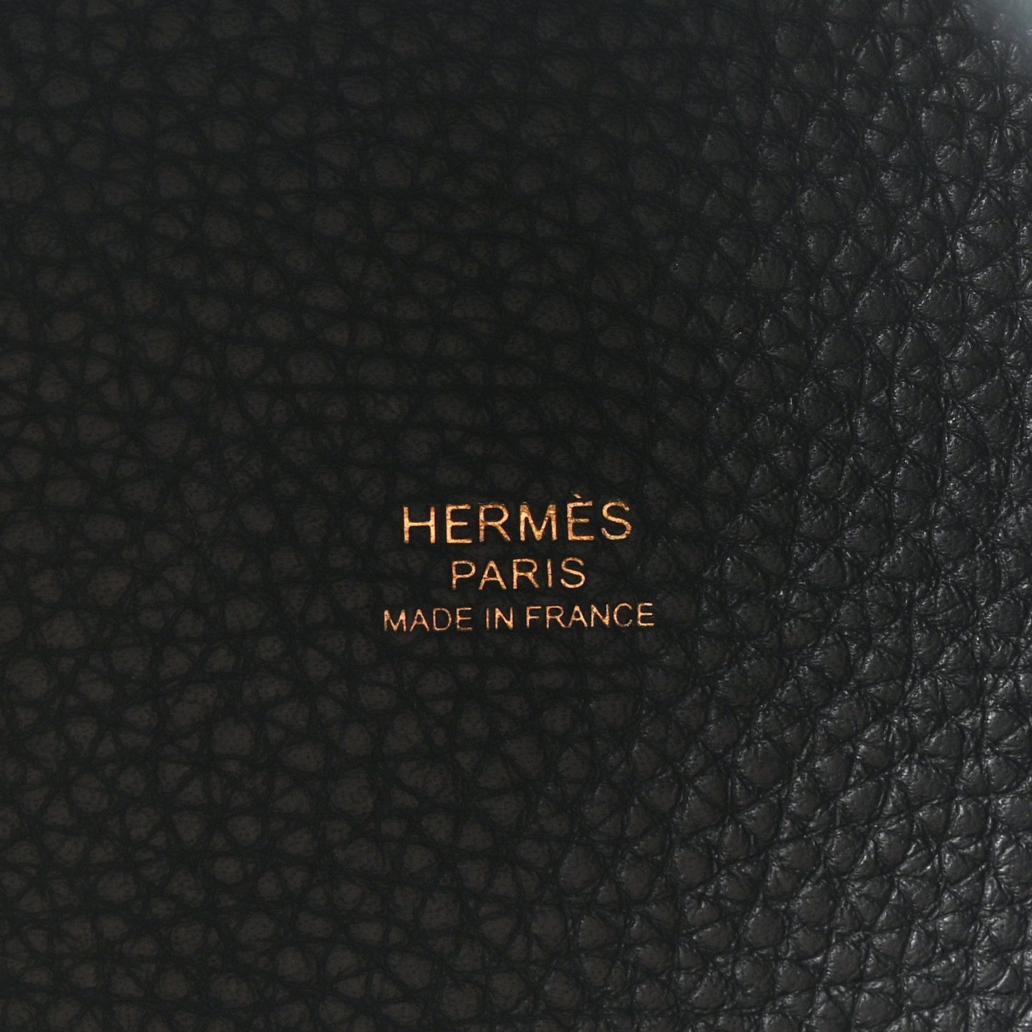 Black leather tote bag centered logo embossing on textured leather surface