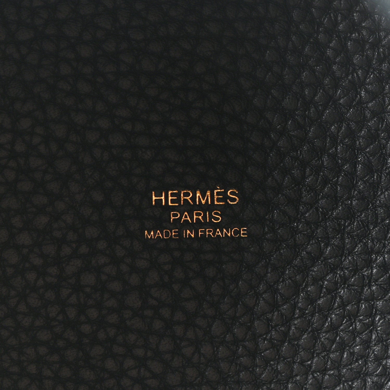 Black leather tote bag centered logo embossing on textured leather surface