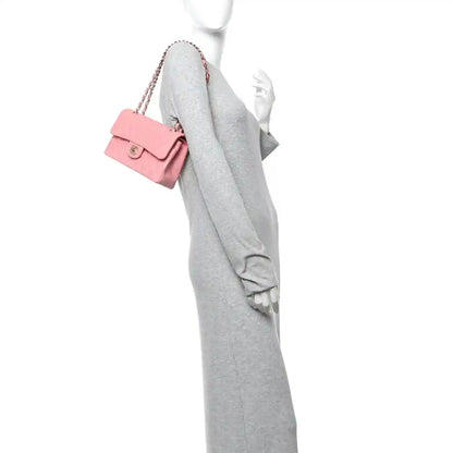 Light pink quilted mini flap bag with gold chain strap, worn on shoulder