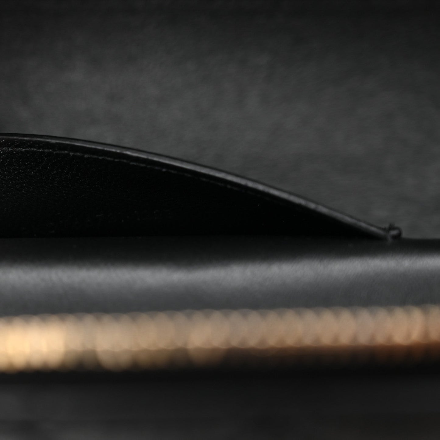 Saint Laurent mini vanity case side view with curved black leather top edge and stitching