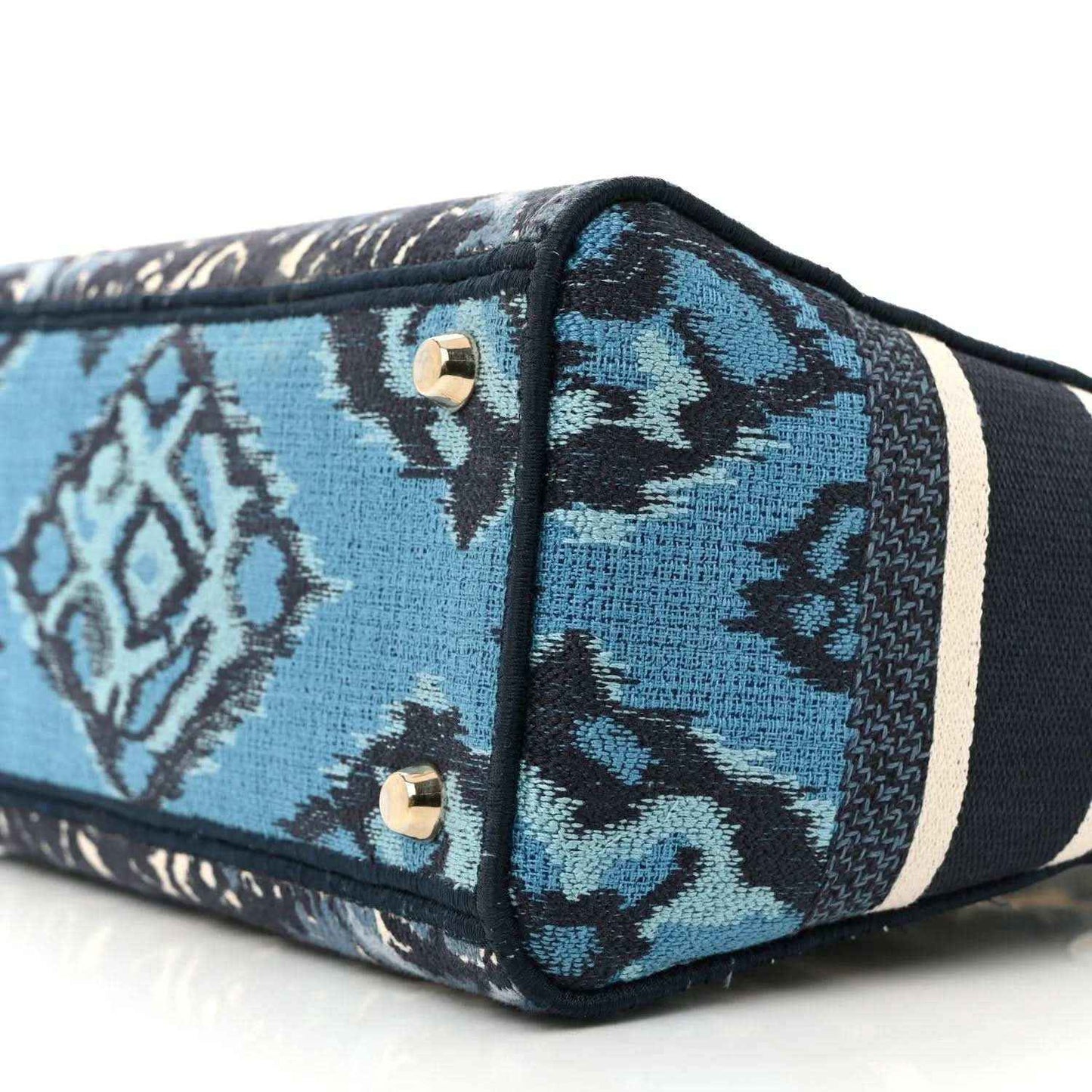 Blue palm toile bag side with black piping, gold snap hardware, and striped trim band