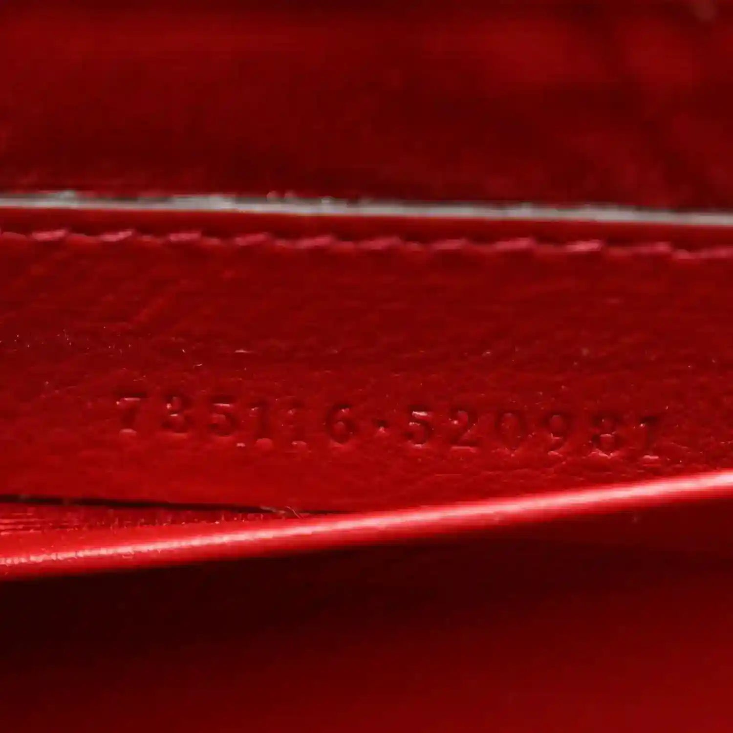Red leather strap detail with embossed stamped text along the edge.