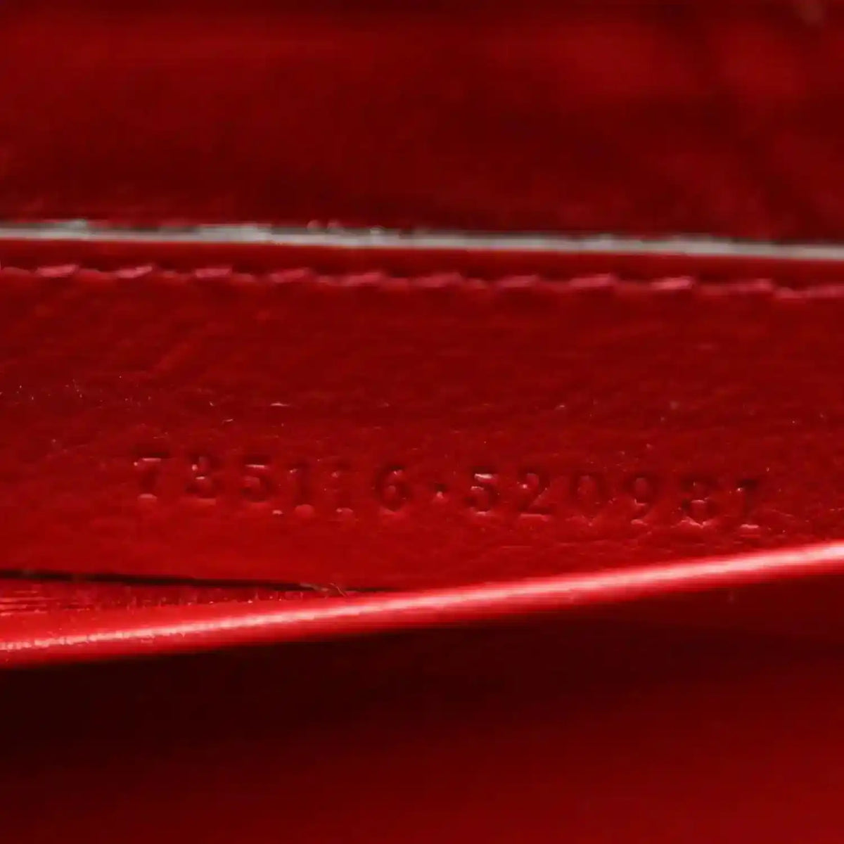 Red leather strap detail with embossed stamped text along the edge.