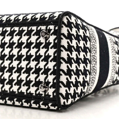 Black-and-white houndstooth canvas bag side with black trim, stud, and strap loop