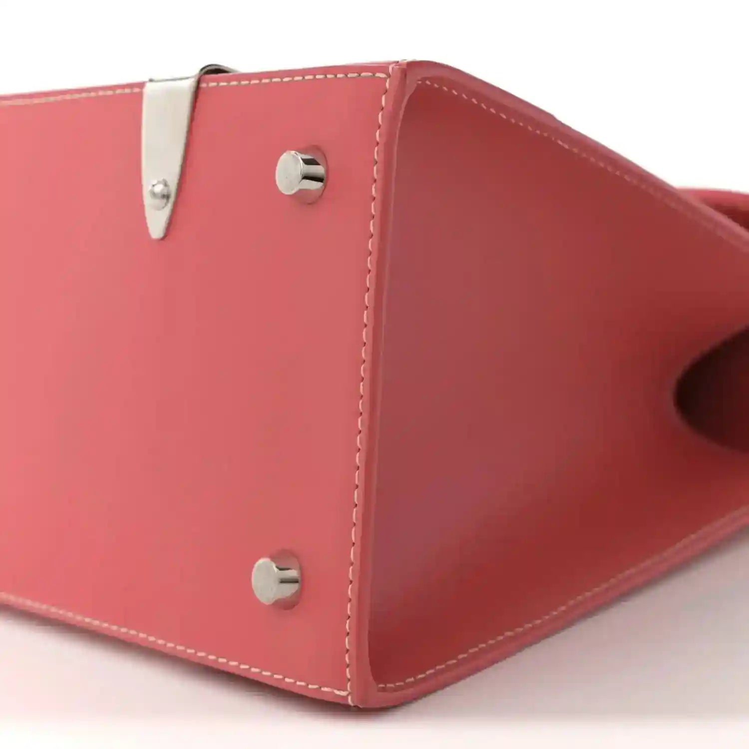 Pink canvas bag corner with silver snap hardware and stitched side panel seams.