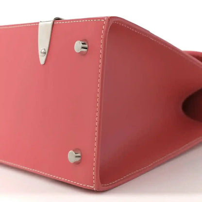 Pink canvas bag corner with silver snap hardware and stitched side panel seams.
