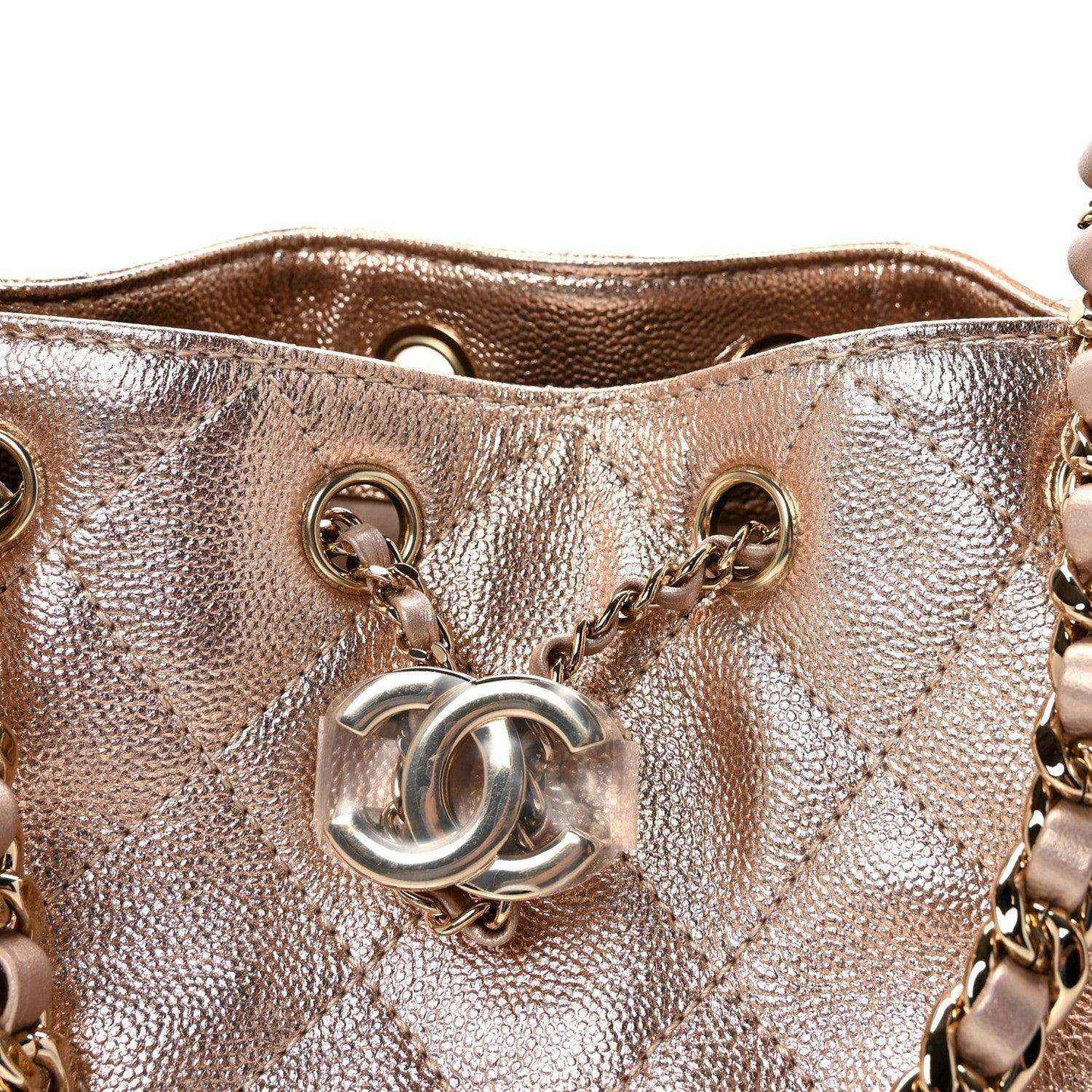 Close-up of copper quilted mini handbag front with CC-style logo and rings.
