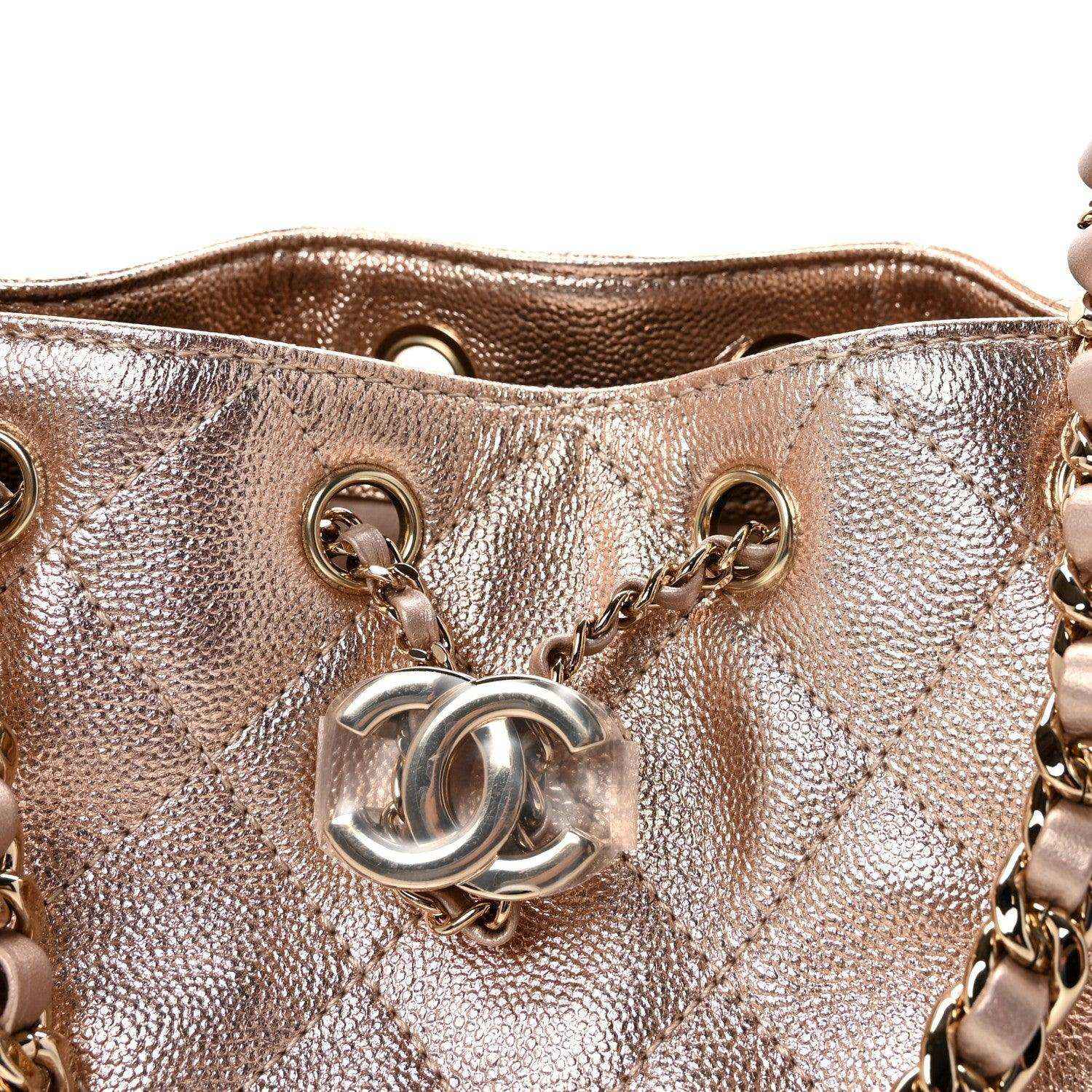 Close-up of copper quilted mini handbag front with CC-style logo and rings.