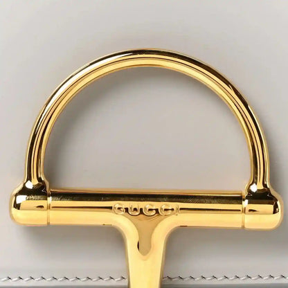 Gold-tone semicircle clasp hardware with Gucci engraving on light grey bag