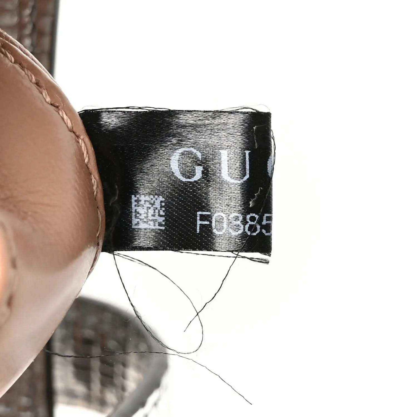 Black fabric care label inside bag with printed code and “GU”