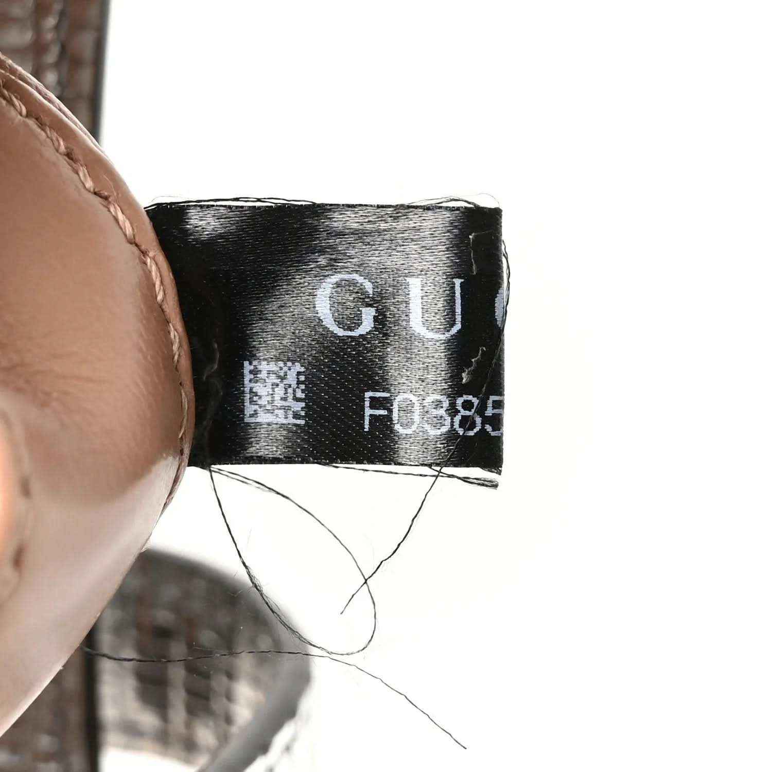 Black fabric care label inside bag with printed code and “GU”
