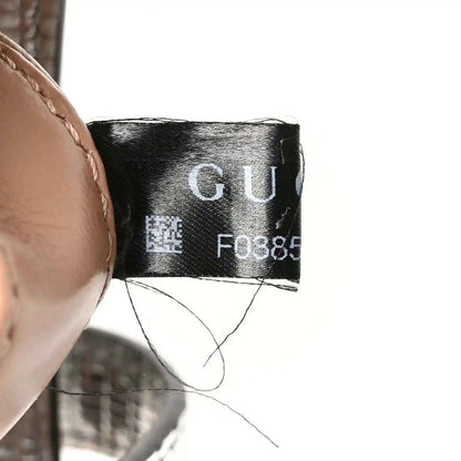 Black fabric care label inside bag with printed code and “GU”