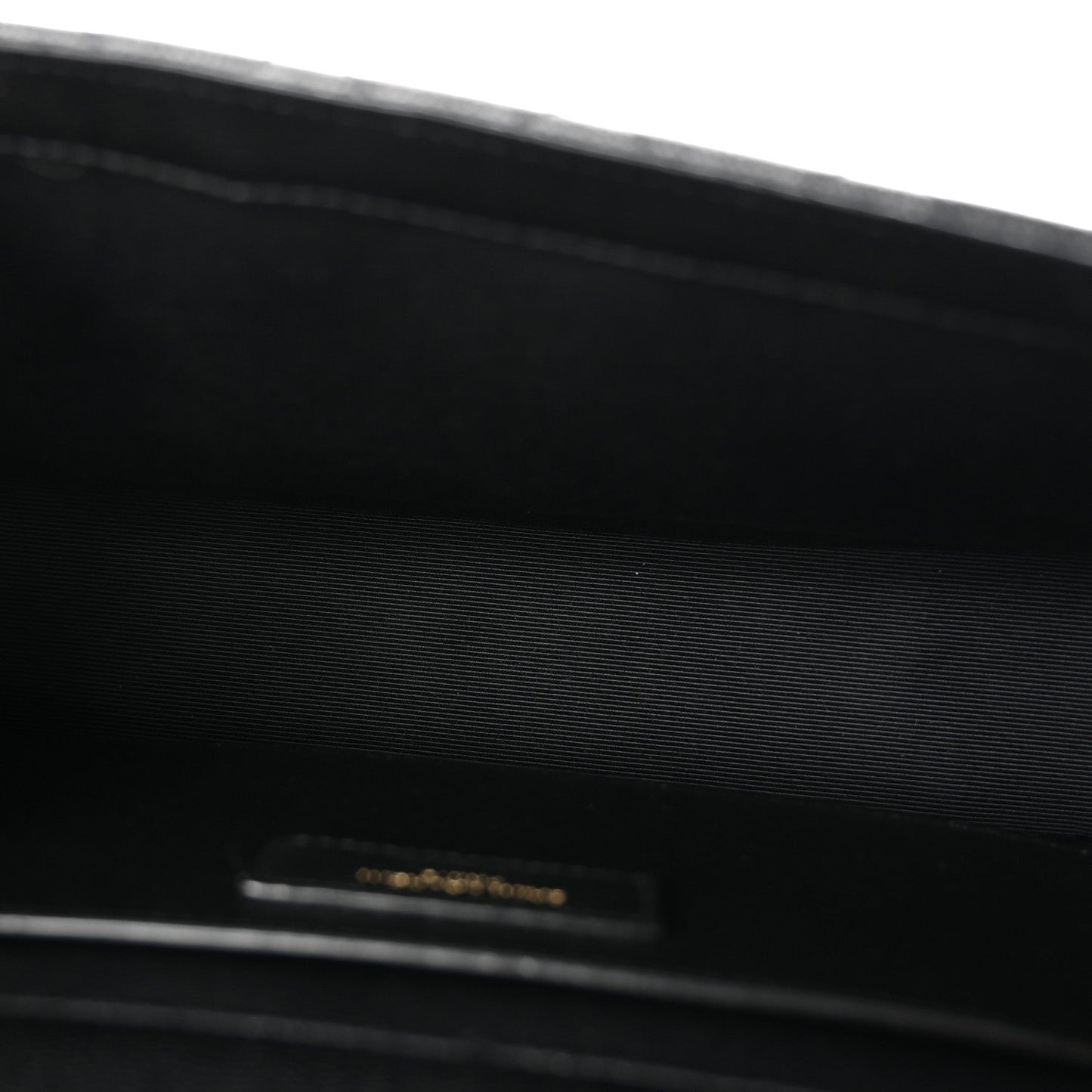 Black satchel interior lining with small gold logo tab near the top edge