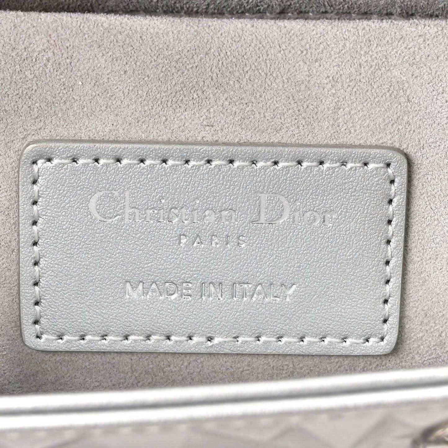 Leather handbag label with embossed text 'Christian Dior' and 'MADE IN ITALY'.