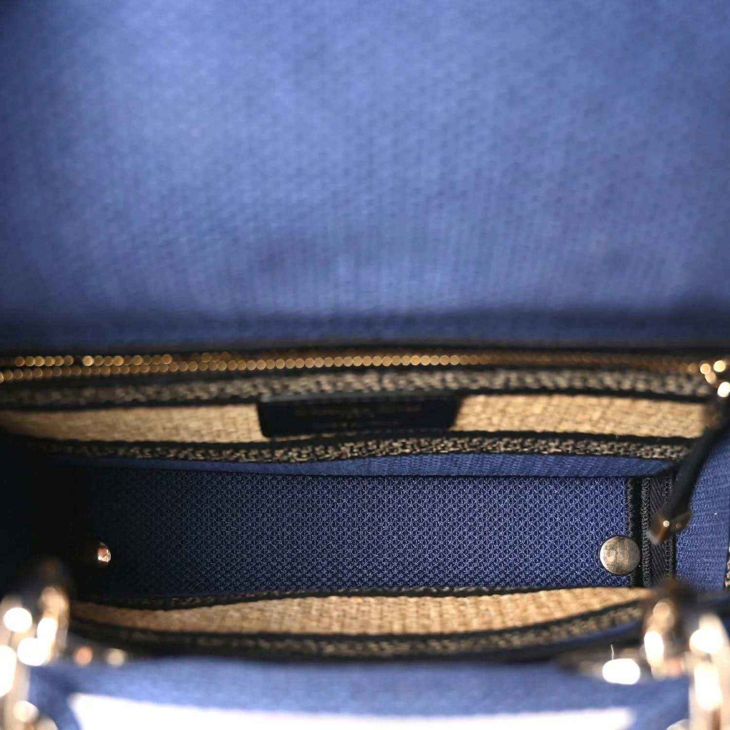 Blue handbag interior view with zipper track and woven striped trim edge