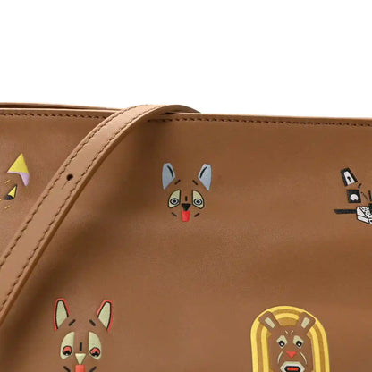 Tan mini clutch front detail with colorful animal face prints and stitched trim.