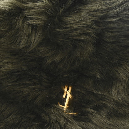 Dark olive shearling bag with gold YSL logo emblem on fur surface