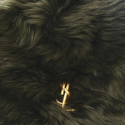 Dark olive shearling bag with gold YSL logo emblem on fur surface