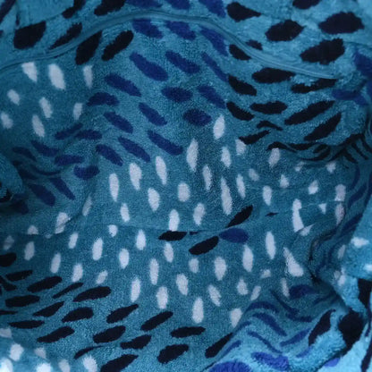 Close-up of turquoise terry tote fabric with black, white, and dark purple animal-style pattern.