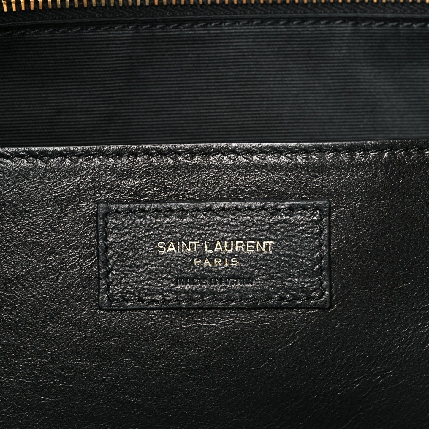 Saint Laurent leather patch with embossed logo on quilted shoulder bag interior.