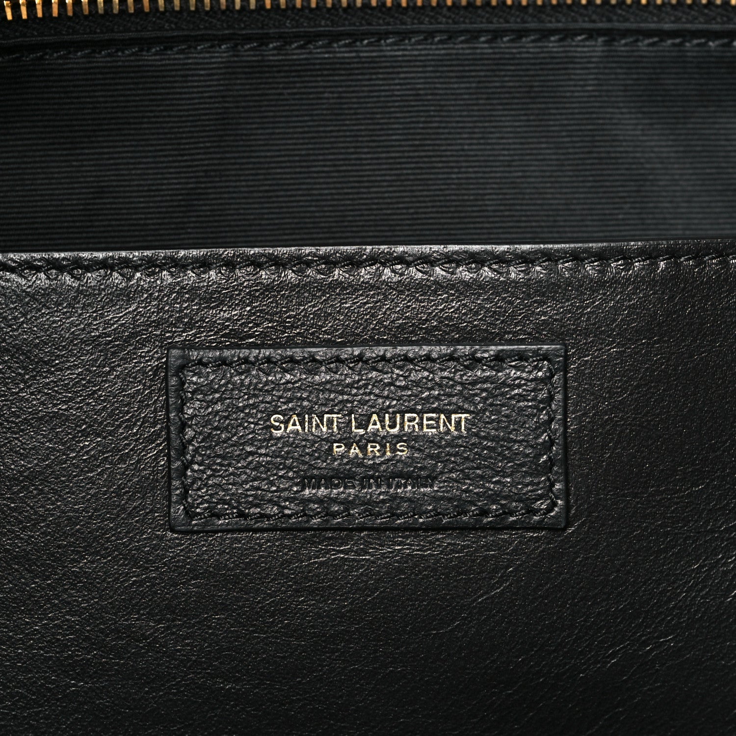 Saint Laurent leather patch with embossed logo on quilted shoulder bag interior.
