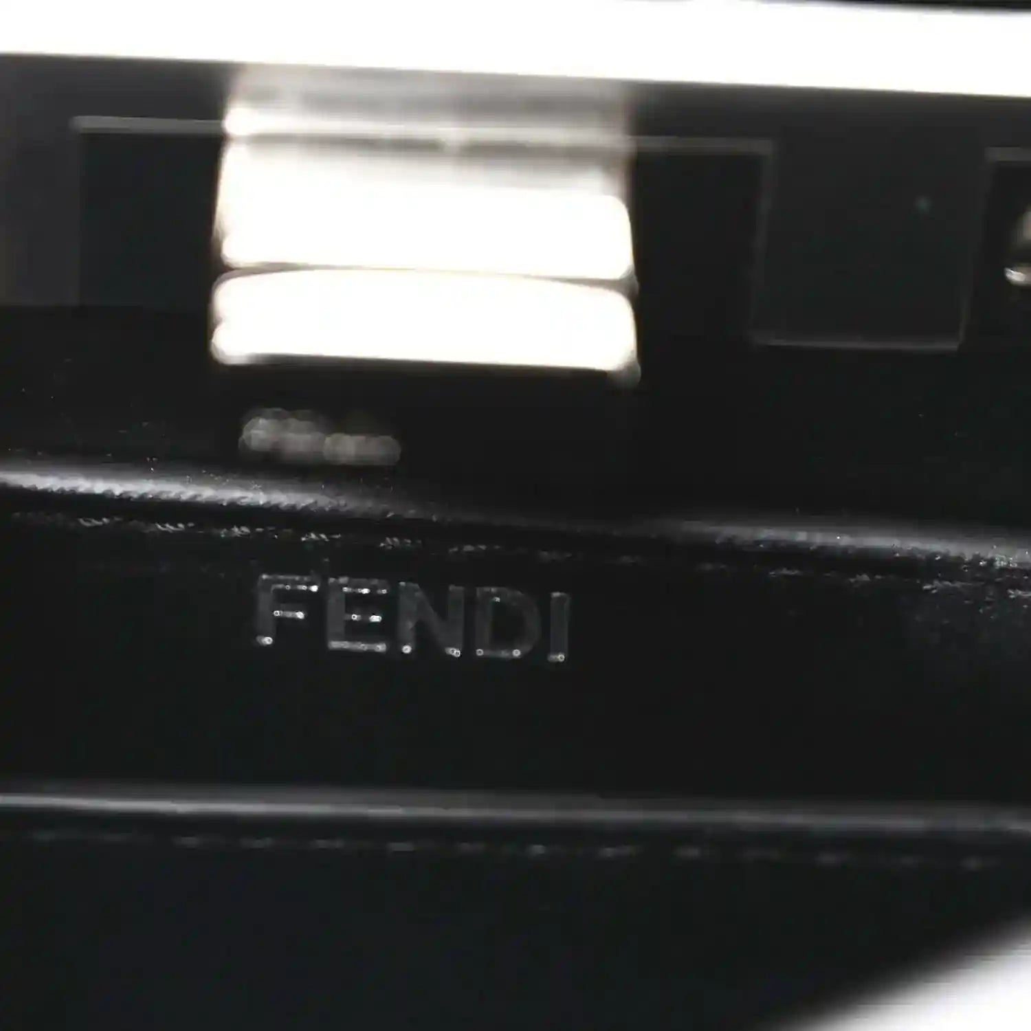 Black leather logo stamp reading 'FENDI' on interior panel