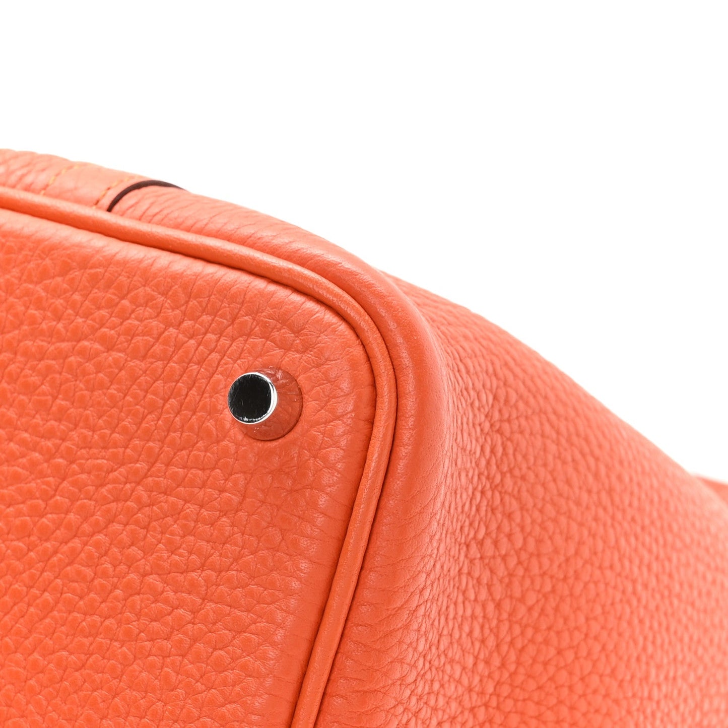 Orange pebbled leather handbag close-up of top seam and metal lock stud