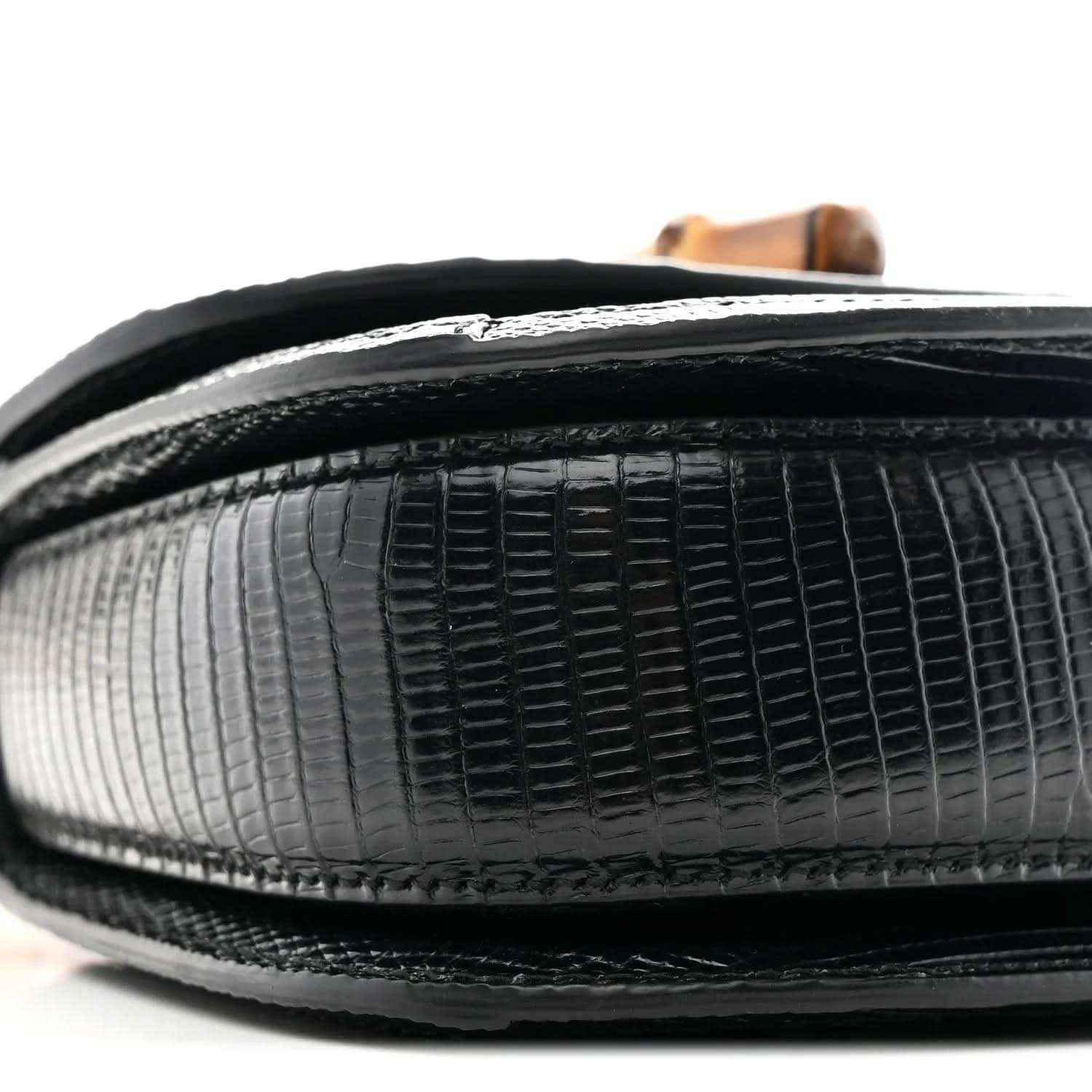 Close-up side of black mini bag with textured leather finish and curved edge