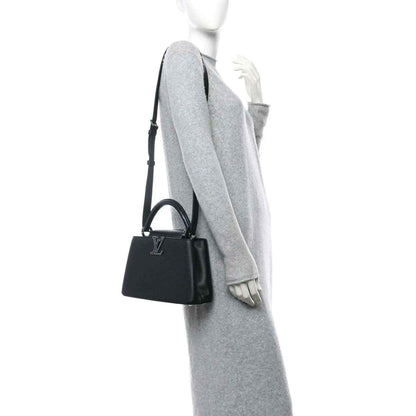Small black leather handbag with top handle, side view, and short strap