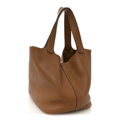 Tan leather tote with wide handles and front lock panel, textured grain