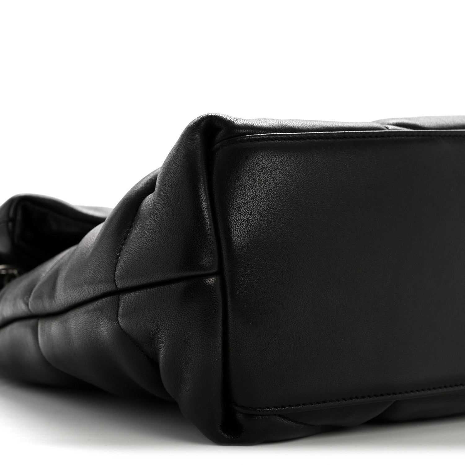 Black quilted satchel corner with smooth leather panel and subtle seam detail