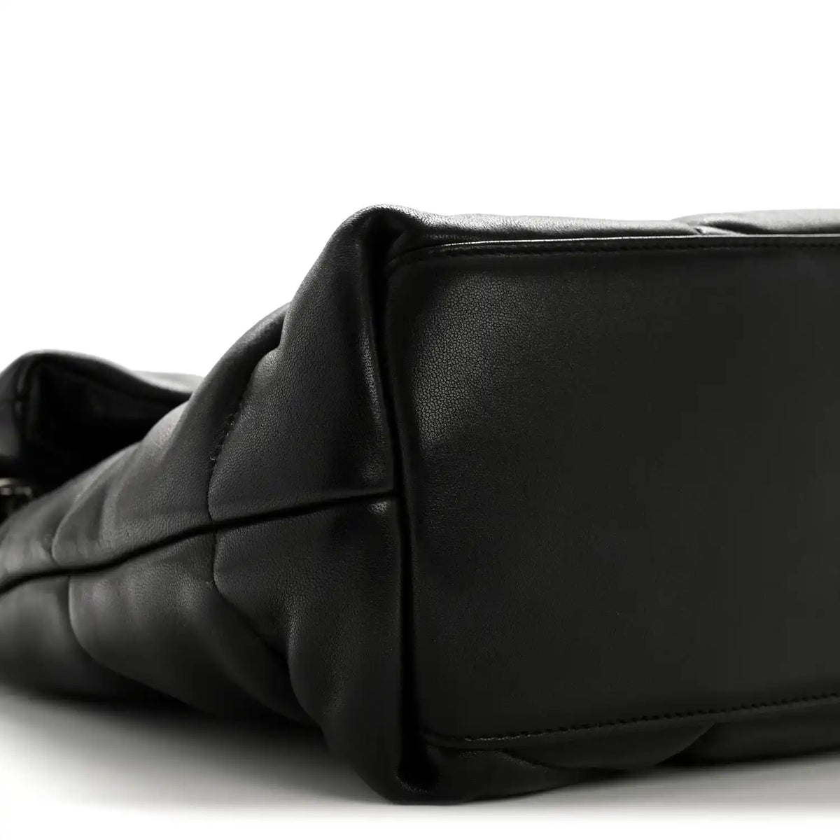 Black quilted satchel corner with smooth leather panel and subtle seam detail