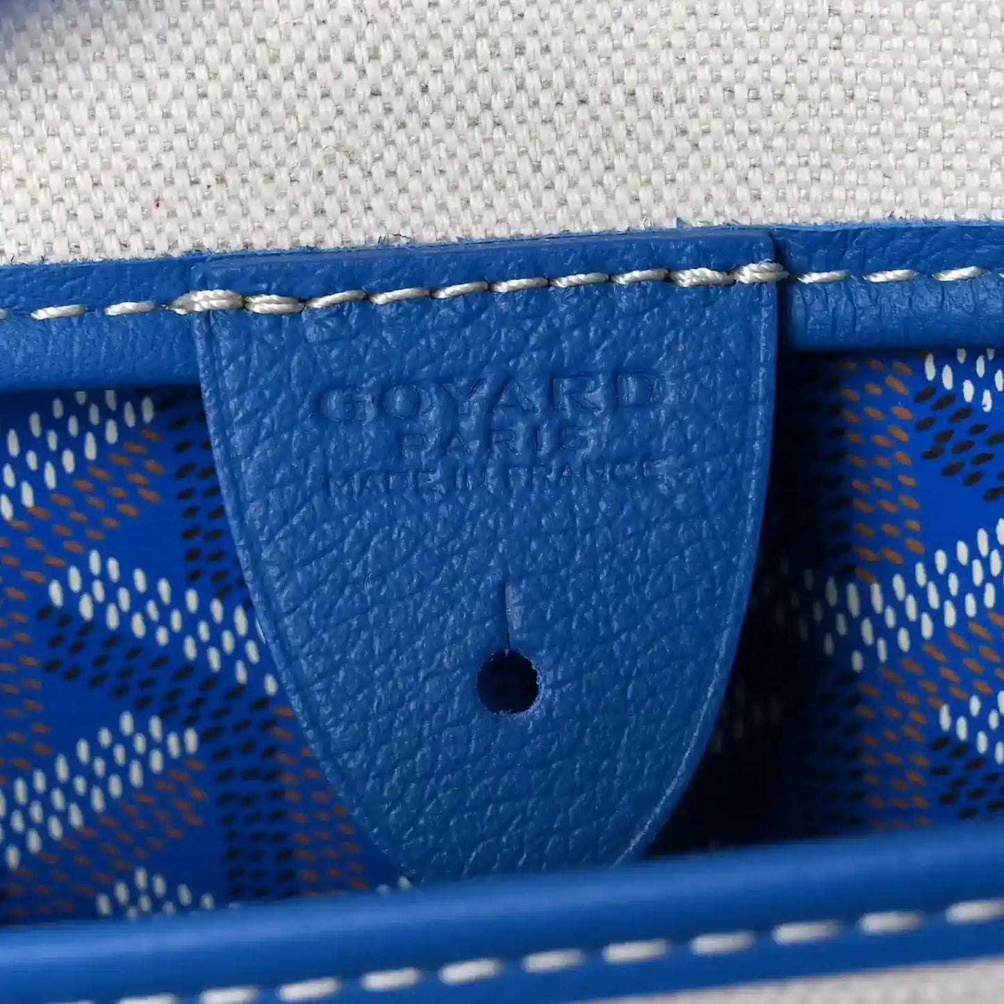 Close-up of sky blue leather trim inside tote bag with embossed logo and stitching