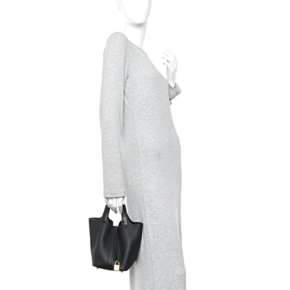 Black leather mini tote with gold lock, held at side