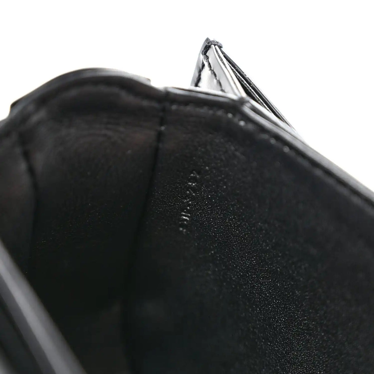 Black shiny mini crossbody bag, close-up of leather edge and open top lining