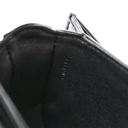 Black shiny mini crossbody bag, close-up of leather edge and open top lining