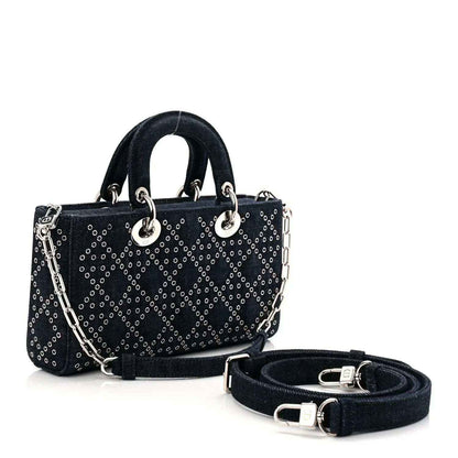 Denim eyelet tote handbag in dark blue with silver-tone hardware, shoulder strap, and charm