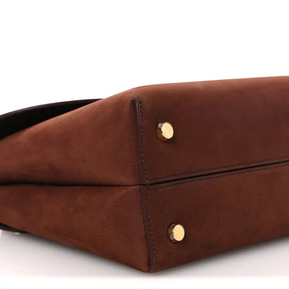 Chestnut brown leather bag corner with gold snap hardware and seam stitching.