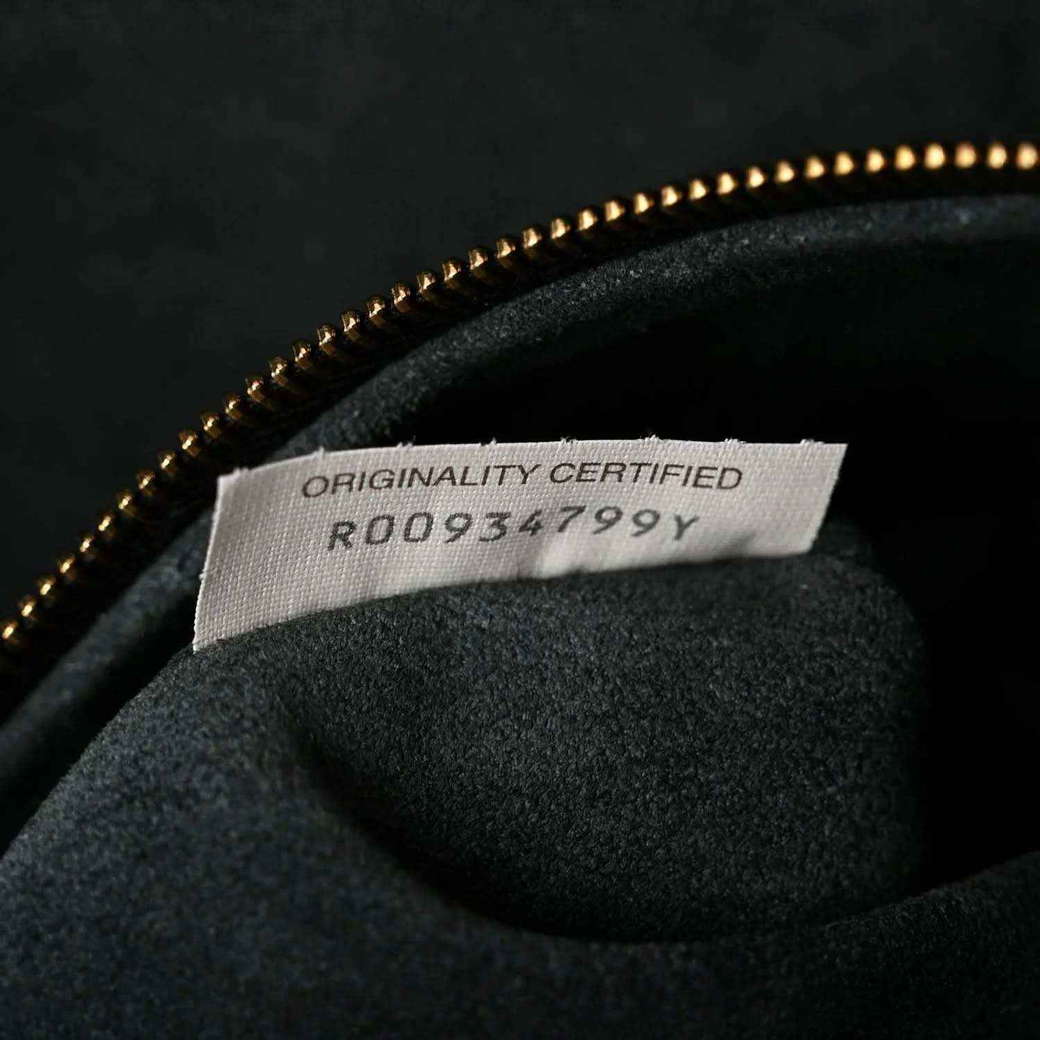 Authenticity label reading ORIGINALITY CERTIFIED inside black bucket bag